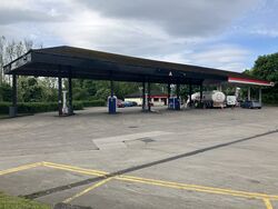HGVs stopped under a black petrol station canopy, with an Esso sign.