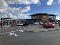 Cars parked in front of a two-storey McDonald's building.