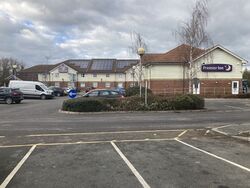 Two-storey building with signs saying Premier Inn, behind a car park.