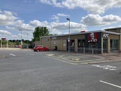 A KFC restaurant with cars parked outside it.
