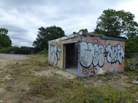 An empty concrete shelter, covered in graffiti.
