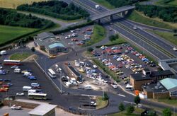 An aerial view of the service area car park and forecourt, next to the motorway.