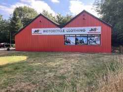 A shop sign saying J&S Motorcycle Clothing, on an old Little Chef restaurant building.