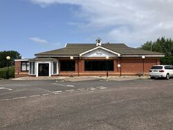 Brick restaurant building in front of a car park.