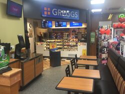 An indoors Greggs unit, with tables in front of it.