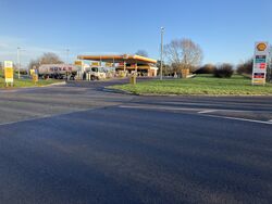 A Shell forecourt in the distance, with a grass verge next to it.