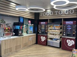 A sign saying Food To Go, with Costa Express machines next to food counters.