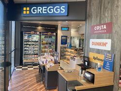 Entrance to a Greggs store from inside a shop.
