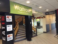 The Waitrose logo, over a flight of stairs.