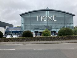 Large glass shopping centre with signs saying Next and Starbucks.