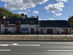 A white, barn-shaped building with dirty Little Chef signage.