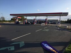 View through an Esso forecourt with a shop, branded SPAR, in a distance.