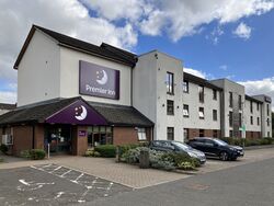 Three-storey hotel building with a Premier Inn sign and cars parked outside it.