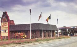 Restaurant building with a flat roof and flagpoles outside, and a sign saying Kelly's Kitchen.