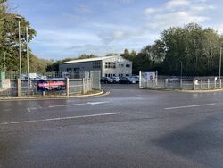 An industrial unit and car park behind a fence, with a sign saying Ashington Automobile Co.