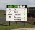 A sign saying Welcome Break, cars, hotel, coaches, caravans, deliveries, all with small arrows.