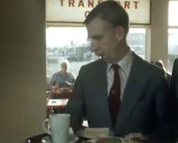 Peter Prior holding a tray with food on it, while inside a café building.