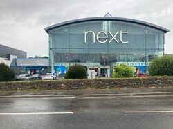 Large glass shopping centre with signs saying Next and Starbucks.