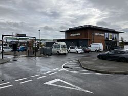 Cars parked in front of a two-storey McDonald's building.