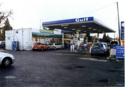 Cars refilling at a Gulf-branded forecourt, with an old-style shop building that is branded Londis, and a sign saying that it's under new ownership.