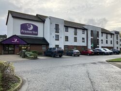 Three-storey hotel building with a Premier Inn sign and cars parked outside it.