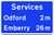 Drawing of a blue road sign saying Services, Odford 2m, Emberry 26m.