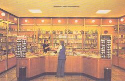 A woman purchasing something at a counter, with rows of goods on display on the shelves behind.