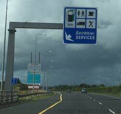 Irish gantry sign above a motorway, showing services.
