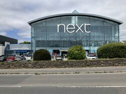Large glass shopping centre with signs saying Next and Starbucks.